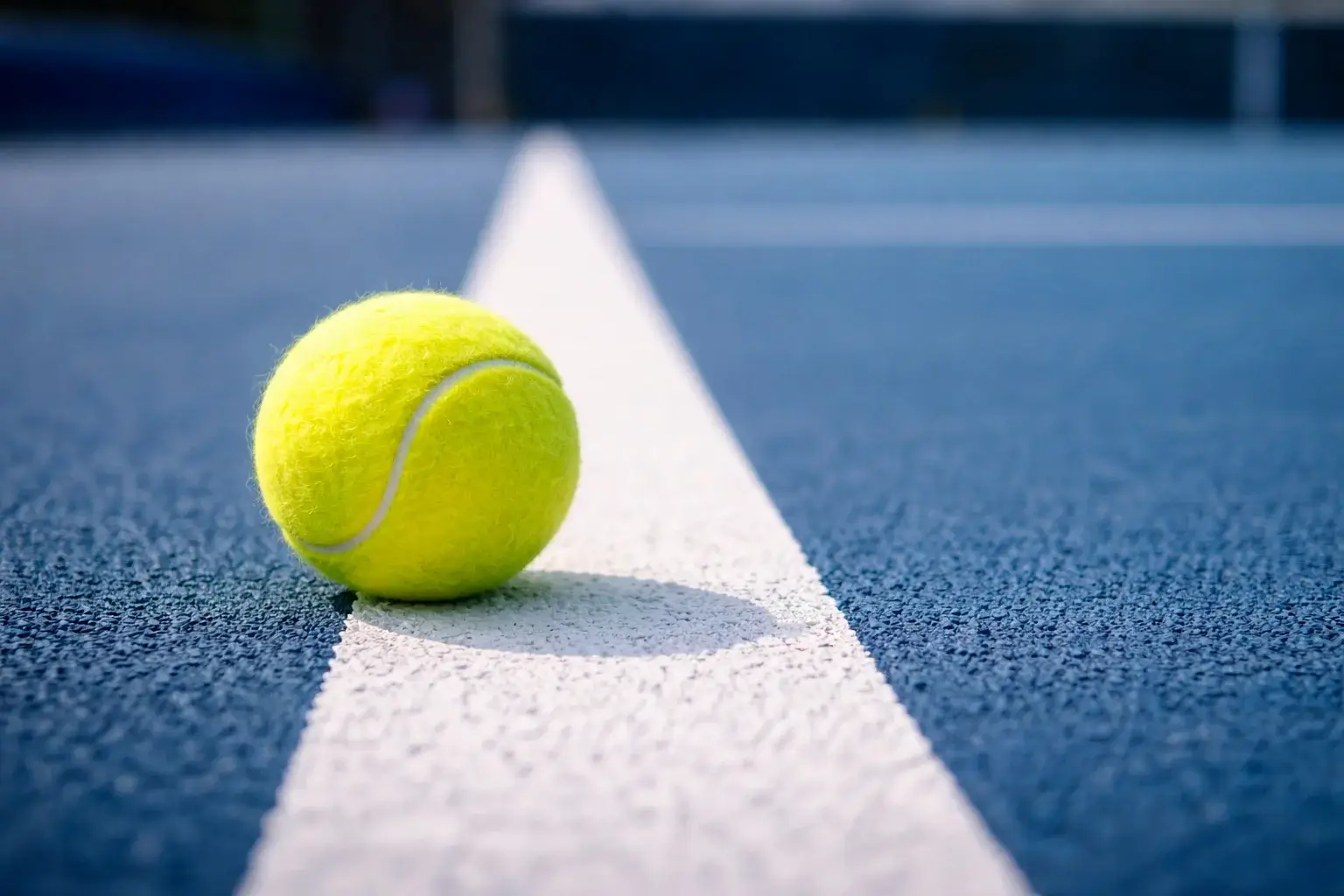 Nahaufnahme eines Tennisballs auf der Grundlinie eines Hartplatzes